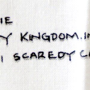May include: Text on a white fabric reads "BY LAURIE FOR DAISY KINGDOM.INC &copy; 1996 # B59201 SCAREDY CAT VEST". The text is in black, handwritten-style lettering.