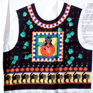 May include: Black vest fabric with a Halloween theme. The design includes a central square with a cat on a pumpkin and the text "I AM NOT A SCARDY CAT". The vest also features pumpkins, black cats, and green leaves.