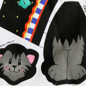 May include: A fabric panel featuring cat-themed designs. The panel includes a cat head with pink ears and a smiling face, and a cat body front. The background has black and white geometric shapes with colorful accents. Text includes "CAT HEAD FRONT" and "CAT BODY FRONT".