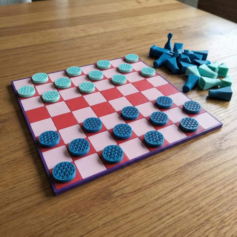 K&ouml;nnte beinhalten: Ein Dame-Spielset mit einem rosa-rot karierten Brett und blauen und t&uuml;rkisfarbenen Spielsteinen. Zus&auml;tzliche blaue Spielsteine sind in der N&auml;he verstreut. Das Brett ist lila umrandet und liegt auf einer Holzoberfl&auml;che.