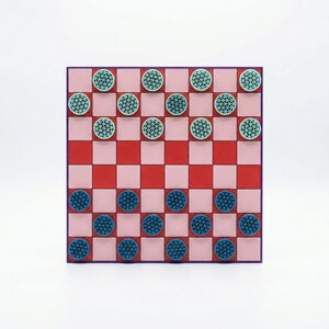 K&ouml;nnte beinhalten: Ein Dame-Spiel mit einem rosa-roten Schachbrettmuster. Das Brett hat einen lila Rand und ist mit t&uuml;rkisfarbenen und blauen Dame-Steinen best&uuml;ckt. Das Spiel befindet sich vor einem wei&szlig;en Hintergrund.