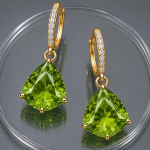 May include: Gold-coloured hoop earrings with a row of small, clear stones. Each earring features a large, triangular, light green gemstone pendant with gold-coloured accents.