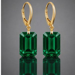 Peut inclure: Une paire de boucles d'oreilles à fermoir levier en or avec des pierres précieuses vertes rectangulaires taille émeraude. Les boucles d'oreilles ont une finition dorée polie et un design pendant classique, mettant en valeur la couleur verte.