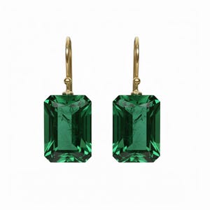 Op de afbeelding: Een paar oorbellen met smaragdgeslepen groene edelstenen met goudkleurige haken. De oorbellen hebben een rechthoekige vorm en zijn gezet in een goudkleurig metaal. De edelstenen zijn heldergroen en lijken gefacetteerd.