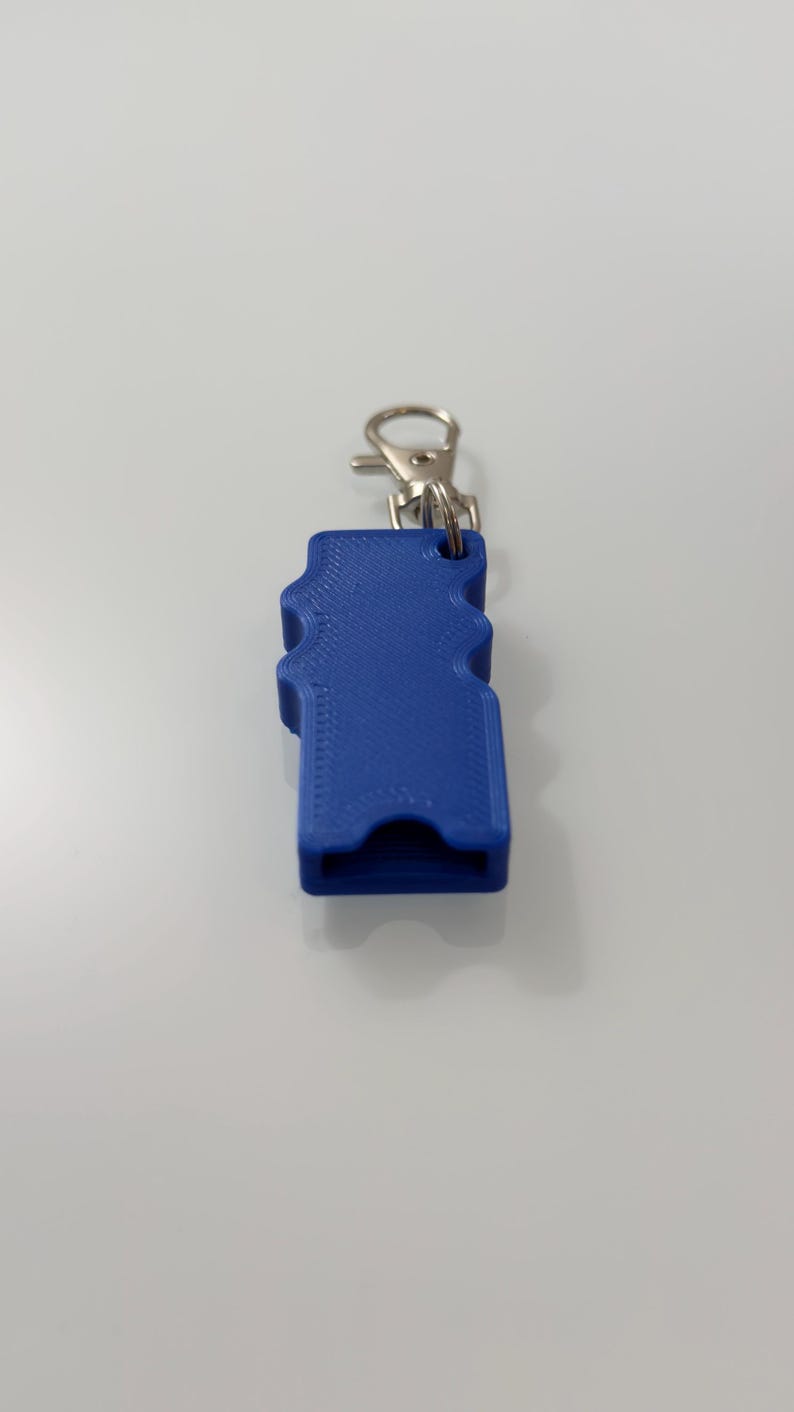 Puede incluir: Un accesorio de llavero azul impreso en 3D con un dise&ntilde;o ondulado. Cuenta con un cierre de metal plateado para sujetarlo a llaves o una bolsa. El llavero es de color azul vibrante.