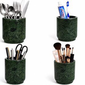 May include: Four cylindrical dark green marble containers with a smooth finish and a stepped base. One holds stainless steel cutlery, another holds a tube of toothpaste and a toothbrush, one holds pens and scissors, and one holds makeup brushes.