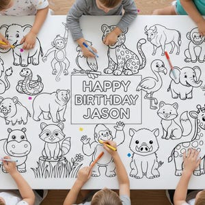 Op de afbeelding: Een groot wit kleurvel met verschillende dieren, waaronder een zebra, een olifant, een leeuw en een giraf. De tekst "HAPPY BIRTHDAY JASON" staat in het midden. Kinderen kleuren de afbeelding met stiften.