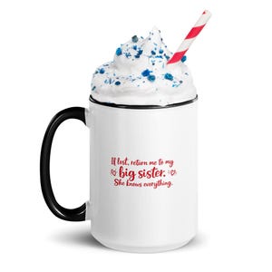 May include: White ceramic mug with a black handle and rim, filled with whipped cream, blue sprinkles, and a red and white striped straw. The mug has the text "If lost, return me to my big sister. She knows everything." in red.