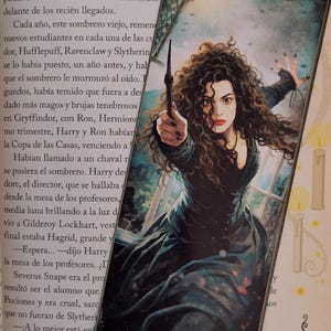 May include: A bookmark featuring a detailed illustration of a woman with dark curly hair, wearing a black dress and holding a wand. The image has a fantasy theme, with a dark and dramatic aesthetic.