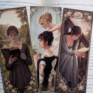 Op de afbeelding: Drie rechthoekige boekenleggers met gedetailleerde illustraties van figuren in historische kleding. De linker boekenlegger toont een lezend persoon, het midden toont twee figuren en rechts een persoon zittend op een trap, allemaal met bloemenranden.
