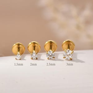 Könnte beinhalten: Vier goldfarbene Ohrstecker mit klaren, runden Zirkonia-Steinen. Die Größen sind 1,5 mm, 2 mm, 2,5 mm und 3 mm. Die Ohrringe werden auf einer hellen Oberfläche präsentiert.
