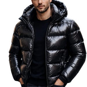 May include: A glossy black puffer jacket with a hooded collar and a zipper closure. The jacket has a shiny, quilted appearance and is worn with a black shirt and dark jeans. The model has his hands in his pockets.