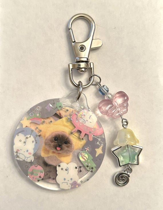 A handmade beaded keychain that frames your custom photo like a holographic Pokémon-style trading card — absurdly niche and totally delightful.