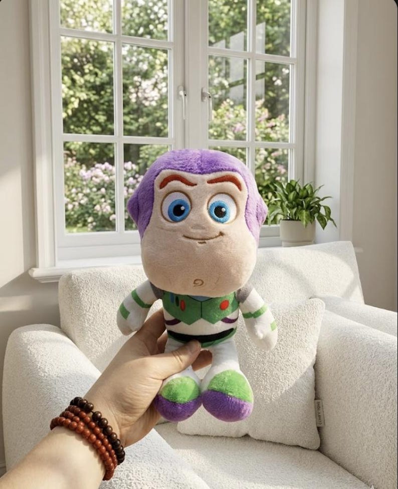 May include: A soft Buzz Lightyear toy, with a purple head, blue eyes, and a friendly smile. The doll is dressed in a green and white spacesuit with purple and green details. The toy is held in front of a window and a white chair.
