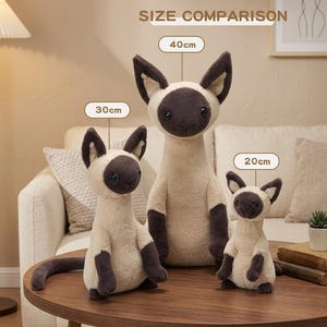 May include: Three plush Siamese cat toys of varying sizes (20cm, 30cm, and 40cm) are displayed on a wooden table. The toys have cream-colored bodies, dark brown faces, ears, paws, and tails. The text "SIZE COMPARISON" is above the toys.