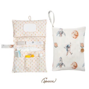 Peut inclure: Un ensemble de change pour bébé crème, comprenant un matelas à langer et un sac assorti. Le matelas à langer comporte un rabat avec un distributeur de lingettes et des poches pour les fournitures. Le sac présente un imprimé sur le thème de l'espace.