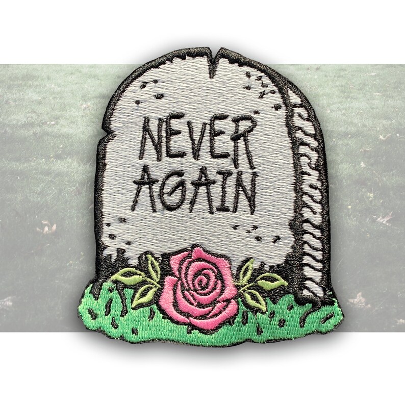 May include: A white tombstone with the words "NEVER AGAIN" inscribed on it. A pink rose with green leaves is at the base of the tombstone.