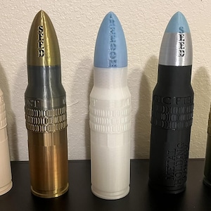 Könnte beinhalten: Fünf dekorative, kugelförmige Objekte in verschiedenen Farben, darunter Weiß, Schwarz und Gold. Jedes hat eine unterschiedlich farbige Spitze und Text auf der Oberseite. Der Text enthält die Wörter "FREEDOM", "SEED" und "MAGIC FIRE".