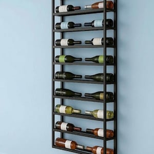 Può includere: Una cantinetta in metallo nero montata su una parete azzurra, contenente diverse bottiglie di vino. La cantinetta ha più ripiani orizzontali, ognuno con una fila di bottiglie di vino. Le bottiglie variano per colore e design dell'etichetta.