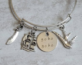 May include: A silver charm bracelet with a ship, sword, bird, and a charm with the text "yo ho yo ho".