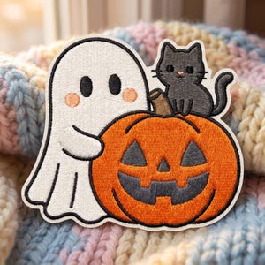 May include: An embroidered patch featuring a white ghost with pink cheeks holding a bright orange jack-o'-lantern. A small black cat sits on top of the pumpkin. The design has a thick white border and is stitched with detailed thread work.