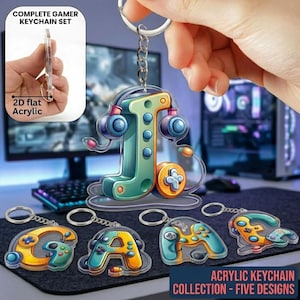 May include: A complete gamer keychain set featuring five acrylic designs. The keychains include a letter "J" with headphones, and the letters "G", "A", and a controller design. The keychains are 2D flat acrylic.