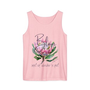 May include: A light pink tank top with a floral design. The design features a watercolor illustration of a protea flower with green leaves and the word "Blom" in cursive. Below the flower are the words "met of sonder 'n pot".