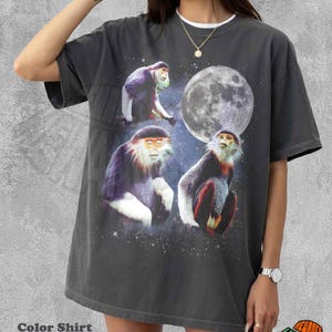 May include: A charcoal grey short-sleeve t-shirt featuring a graphic print of three red-shanked douc langurs positioned against a starry night sky with a large full moon. The shirt has a crew neckline and a relaxed, boxy fit with a faded finish.