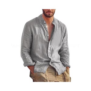 Puede incluir: Una camisa gris claro de manga larga con cuello mandarín y botones. La camisa está hecha de una tela ligera y tiene las mangas enrolladas. El modelo lleva pantalones de color caqui.