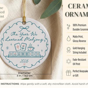 May include: A round white ceramic ornament with a 3-inch diameter, featuring a teal decorative border, a gold hanging string, and the text The Year We Learned Mahjong 2026. The design includes illustrations of mahjong tiles and a teacup.