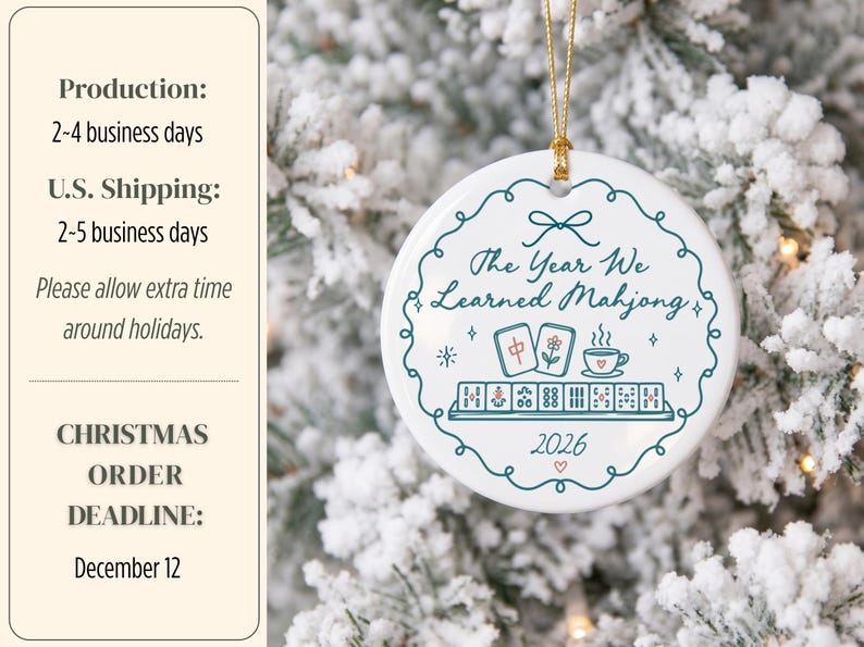 May include: A round white ceramic ornament hanging by a gold string. The design features a teal scalloped border, the text The Year We Learned Mahjong, illustrations of mahjong tiles and a teacup, and the year 2026 in teal and red ink.