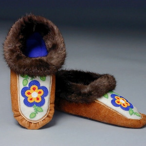 A pair of moccasins made from the moccasin pattern. They have leather soles, beaded vamps and fur trim.