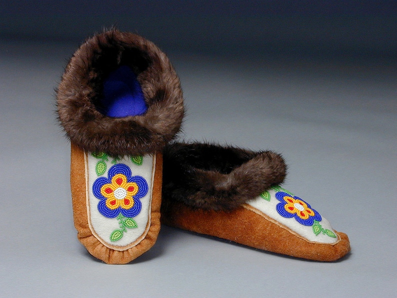 A pair of moccasins made from the moccasin pattern. They have leather soles, beaded vamps and fur trim.