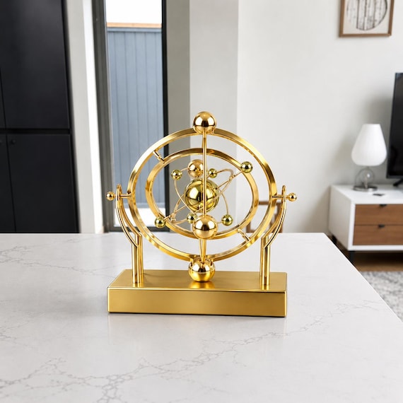 A brass-and-steel celestial orbit pendulum that models planetary motion on your desk — equal parts physics toy, astronomy art, and perpetual conversation starter.