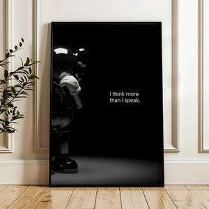 Puede incluir: Impresi&oacute;n art&iacute;stica enmarcada en negro con una figura negra brillante con guantes blancos y una cruz blanca en cada mano. El texto "I think more than I speak" se muestra en blanco sobre un fondo negro.