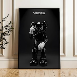 Puede incluir: Impresi&oacute;n art&iacute;stica enmarcada en negro que presenta una figura negra brillante con guantes blancos y ojos tachados, sentada en un taburete. La impresi&oacute;n incluye el texto "A CALM MIND CREATES POWERFUL FUTURES" en letras blancas sobre un fondo negro.