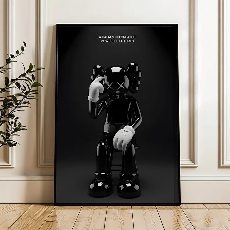 Puede incluir: Impresi&oacute;n art&iacute;stica enmarcada en negro que presenta una figura negra brillante con guantes blancos y ojos tachados, sentada en un taburete. La impresi&oacute;n incluye el texto "A CALM MIND CREATES POWERFUL FUTURES" en letras blancas sobre un fondo negro.