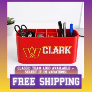May include: A red rectangular desk organiser with multiple compartments containing scissors, a stapler, paper clips, thumbtacks, and pens. The front of the organiser features a yellow and white logo with the text CLARK in bold white letters.