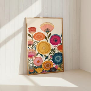 May include: A framed floral art print featuring a vibrant array of stylized flowers. The artwork showcases blooms in shades of pink, orange, yellow, and blue, set against a cream background. The print is encased in a light brown wooden frame.
