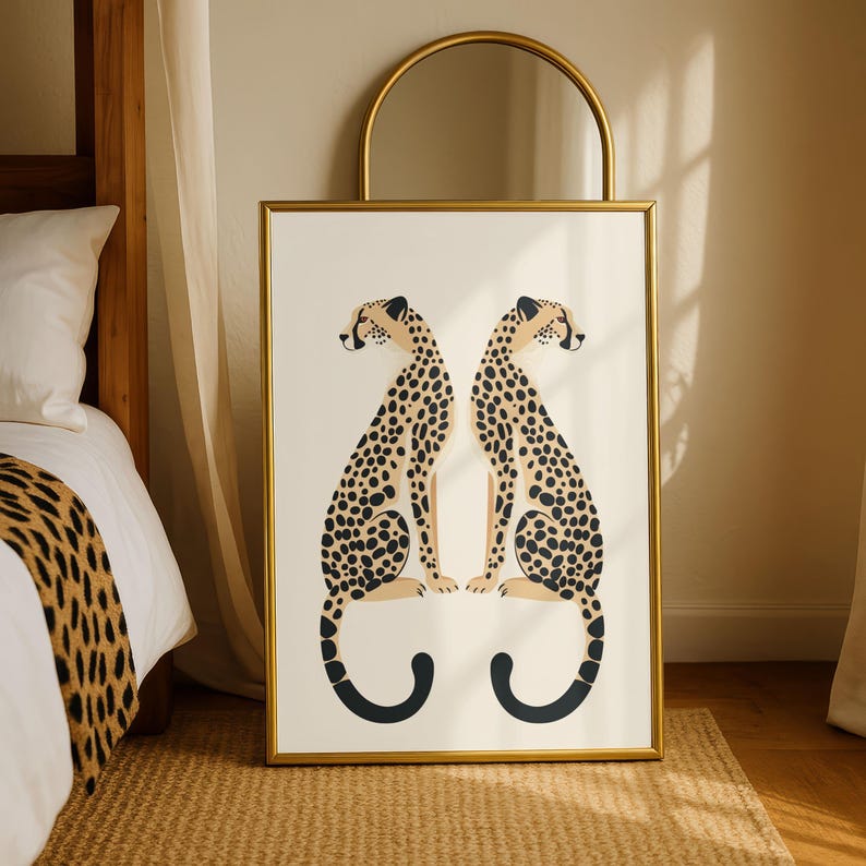 May include: A framed art print featuring two stylized cheetahs facing each other. The cheetahs have tan bodies with black spots and are set against a cream background. The frame is gold, and the artwork is displayed in a bedroom setting.