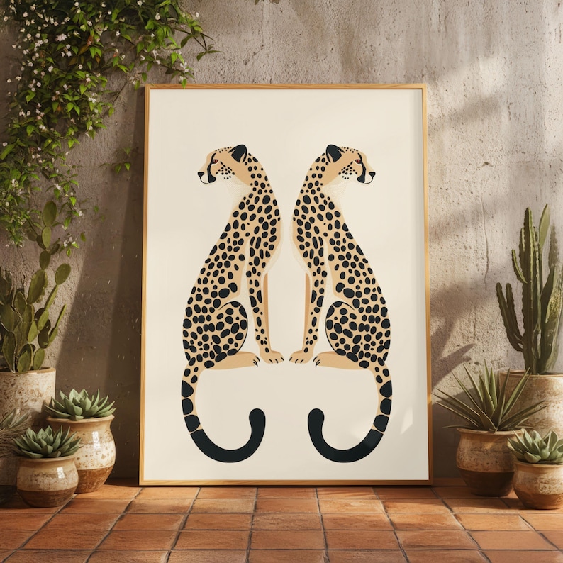 May include: Framed art print featuring two stylized cheetahs facing each other. The cheetahs have tan bodies with black spots and black tails. The background is off-white, and the frame is a light brown color. The print is displayed on a brick surface.