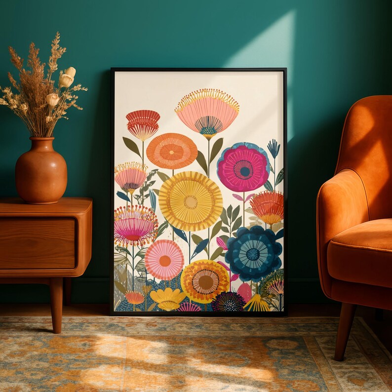 May include: A framed floral art print featuring colorful, stylized flowers in shades of pink, orange, yellow, and blue against a white background. The artwork is in a black frame and is displayed in a room with a teal wall and an orange chair.