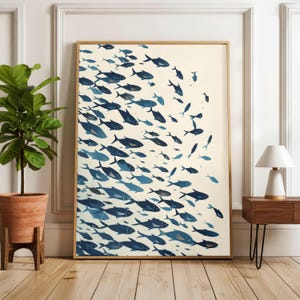 Puede incluir: Un cuadro enmarcado con una escuela de peces azules sobre un fondo crema. Los peces, de varios tamaños y tonos, crean un efecto dinámico. La obra de arte se presenta en un marco de madera, ideal para la decoración.