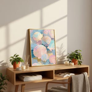 Puede incluir: Una impresi&oacute;n art&iacute;stica enmarcada con un dise&ntilde;o de acuarela de conchas marinas en colores pastel. La obra de arte tiene un marco dorado y se exhibe sobre una consola de madera. La escena incluye plantas en macetas, velas y objetos decorativos.