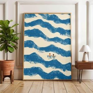 Può includere: Una stampa artistica incorniciata con un'illustrazione stilizzata di due persone che nuotano tra le onde blu. L'opera d'arte ha un'estetica minimalista con uno sfondo color crema e una cornice in legno. La stampa è esposta in una stanza con una pianta e una lampada.
