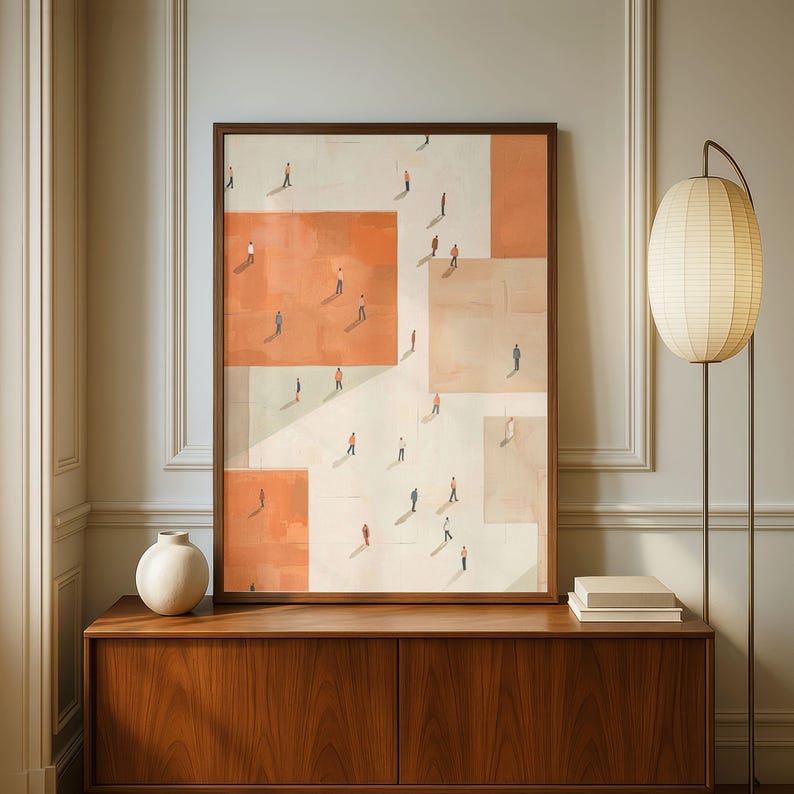 May include: A framed abstract art print featuring a geometric design with orange and beige squares. Small figures are depicted walking across the surface. The artwork is displayed above a wooden cabinet, with a lamp and vase nearby.