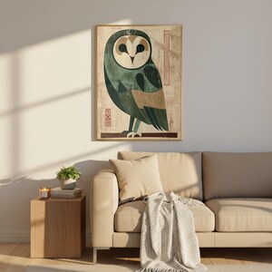 Op de afbeelding: Een ingelijste kunstdruk met een gestileerde uil-illustratie. De uil is afgebeeld in tinten groen, beige en bruin, met een geometrisch ontwerp. De achtergrond heeft een vintage papiertextuur. Het kunstwerk is in een gouden lijst.