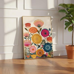 May include: A framed art print featuring a colorful floral design. The artwork showcases a variety of stylized flowers in shades of pink, orange, yellow, and blue against a cream background. The frame is gold-toned, adding a touch of elegance.