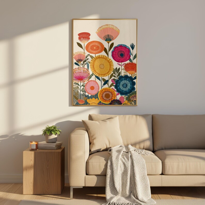 May include: A framed floral art print featuring colorful stylized flowers in shades of pink, orange, yellow, and blue. The artwork has a gold frame and is displayed on a white wall above a beige sofa.