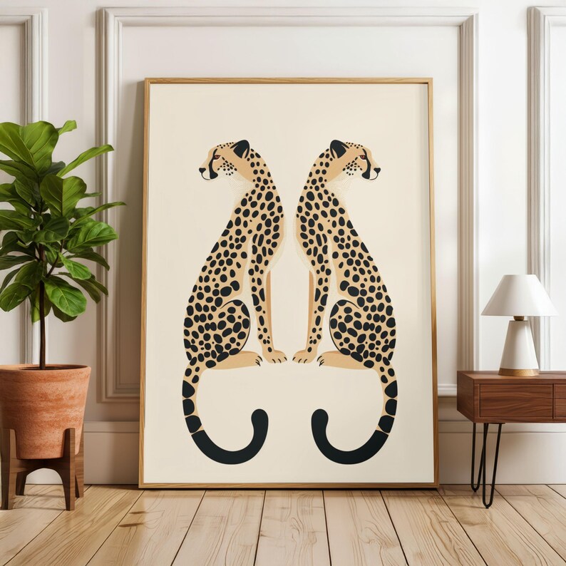 May include: A framed art print featuring two stylized cheetahs facing each other. The cheetahs have tan bodies with black spots and black curved tails. The background is a cream color, and the frame is gold.